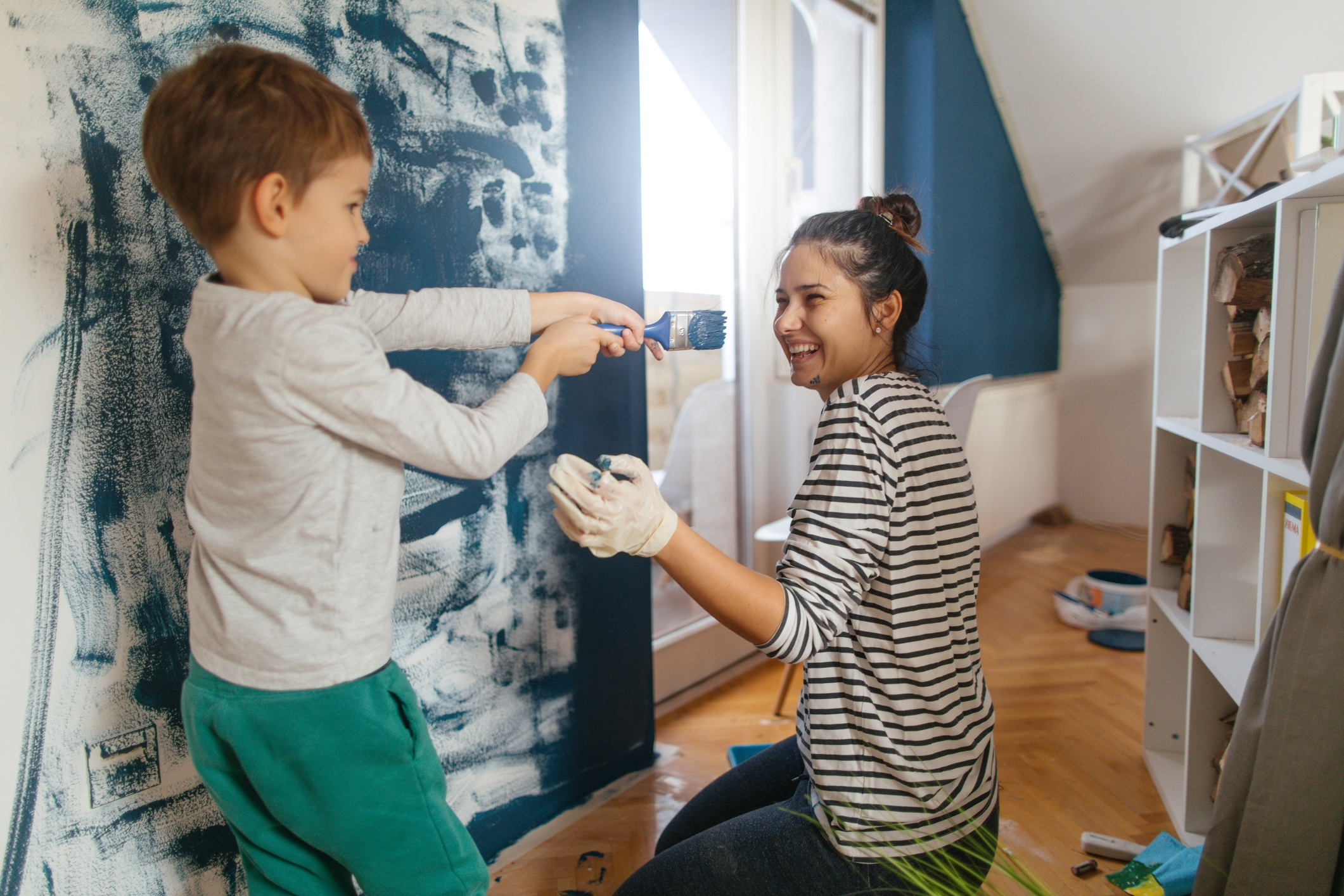 Mother and son working together on repainting a wall in their living room